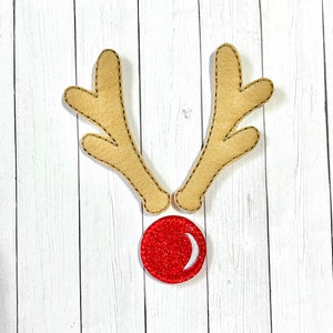 May include: A pair of brown felt reindeer antlers with a red felt nose with a white crescent moon design.