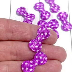 May include: Purple satin bows with white polka dots. The bows are small and perfect for adding a touch of whimsy to crafts and projects.