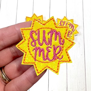 May include: A yellow sun-shaped patch with a pink embroidered "Summer" design. The patch has a glittery texture.