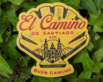 May include: Yellow sticker with a black and white illustration of a seashell with a road leading to a church. The text "El Camino de Santiago ESP. Buen Camino" is printed on the sticker.