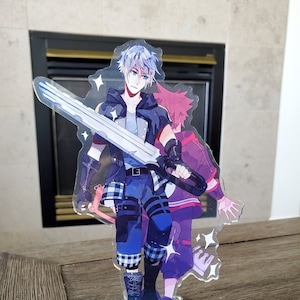 May include: A clear acrylic stand featuring two anime characters, one with blue hair and a sword, the other with pink hair. The characters are standing on a blue and white wave design with a brown log.
