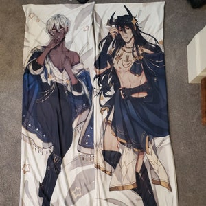 May include: Two body pillows with illustrations of two characters. One character has white hair and is wearing a blue and white robe. The other character has black hair and is wearing a blue and gold robe. Both characters are wearing black boots.