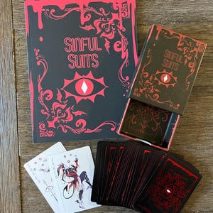 May include: A playing card set and book titled "Sinful Suits" with a black and red color scheme. The book and card box feature a red eye design. Several playing cards are visible, including a Joker card.