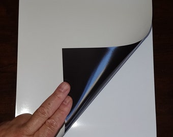 May include: A white sheet of paper with the text "Property of Siglian" printed on it. The paper has a black magnetic backing that is being peeled back.