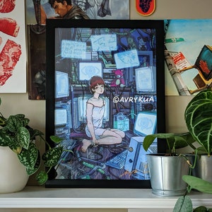 Può includere: Una stampa incorniciata di un'illustrazione digitale che rappresenta una donna con capelli castano corti seduta in una stanza piena di schermi di computer. La donna indossa un vestito bianco e guarda verso il basso uno schermo. La stampa è incorniciata in nero e ha un passepartout bianco. Il testo "@AVRYKIA" è visibile nell'angolo in basso a destra della stampa.