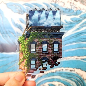 Puede incluir: Una pegatina de un edificio de ladrillo con una valla publicitaria en la parte superior. El edificio está parcialmente derrumbado y tiene enredaderas que crecen por el lado. La valla publicitaria tiene un cielo azul con nubes blancas y focos que brillan hacia abajo. La pegatina está sobre un fondo azul y blanco.