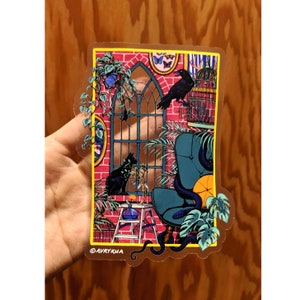 May include: A sticker featuring a colourful illustration of a room with a window, a chair, a birdcage, a cat, and a bird. The room is decorated with plants and flowers. The sticker is on a wooden surface. ©AVRYKUA