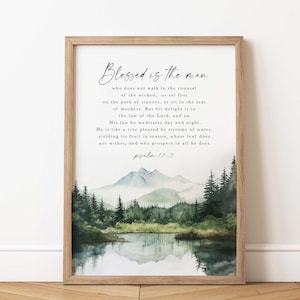 May include: A framed print with a watercolor painting of a lake and mountains. The print features a Bible verse from Psalm 11:3, "Blessed is the man who does not walk in the counsel of the wicked, or set foot on the path of sinners, or sit in the seat of mockers. But his delight is in the law of the Lord, and on his law he meditates day and night. He is like a tree planted by streams of water, yielding its fruit in season, whose leaf does not wither, and who prospers in all he does."