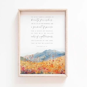 Könnte beinhalten: Ein Aquarellbild einer Berglandschaft mit einem Feld voller Wildblumen im Vordergrund. Das Bild enthält ein Zitat aus der Bibel, Jesaja 61,3, das lautet: "Um ihnen eine Krone der Schönheit für Asche zu geben, das Öl der Freude für Trauer und ein Gewand des Lobes für einen Geist der Verzweiflung. So werden sie Eichen der Gerechtigkeit genannt werden, die Pflanzung des Herrn, damit er verherrlicht werde."