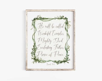 May include: A rectangular wall art print in a light wood frame featuring the text He will be called Wonderful Counselor, Mighty God, Everlasting Father, Prince of Peace, Isaiah 9:6, surrounded by a decorative border of green ribbons and leaves.