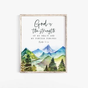May include: A framed watercolour print depicting a mountain scene in blue, green, and yellow hues. The artwork includes the text "God is the strength of my heart and my portion forever Psalm 73:26" in black script.