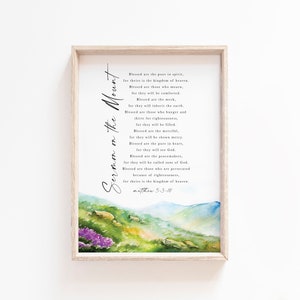 May include: A framed print featuring the text "Sermon on the Mount" in elegant script. The artwork includes a watercolor landscape with mountains and flowers in shades of green, blue, and purple. The text is from Matthew 5:3-10.