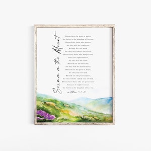 May include: Framed print featuring the text "Sermon on the Mount" in elegant script. The artwork includes a watercolor landscape with green hills, purple flowers, and a blue sky. The text is a passage from Matthew 5:3-10.