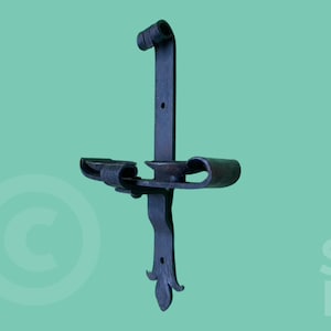 May include: A black metal wall-mounted candle holder with a fleur-de-lis design. The holder has two arms that extend out to hold candles.