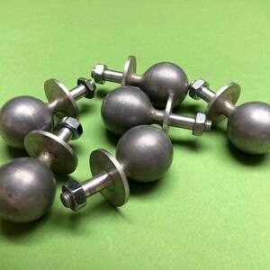 以下が含まれることがあります： 丸いボール型の形状と平らなベースを持つ、銀色の金属製のノブが6つあります。ノブのベースの中央にはねじ穴があります。