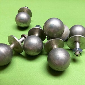 以下が含まれることがあります： 丸いノブが付いた銀色の金属製の引き出しの取っ手が6つあります。取っ手はシンプルなデザインで、丸いベースに取り付けられています。