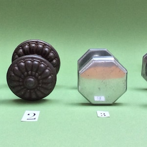 Könnte beinhalten: Vier verschiedene Türknauf, zwei sind dunkelbraun und zwei sind silber. Die Knäufe sind in einer Reihe von links nach rechts angeordnet und von 1 bis 4 nummeriert.