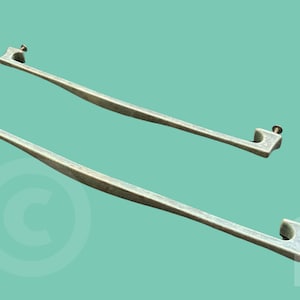 May include: Two silver metal cabinet door pulls with a rectangular shape and a slight curve. The pulls have a simple design with a small hole at each end for mounting.