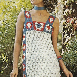 May include: A white crochet maxi dress with a geometric pattern and red, white and blue accents. The dress has a sleeveless design and a square neckline. The model is wearing a blue ribbon around her neck.