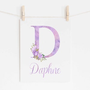 Op de afbeelding: Paarse aquarelletter D met een bloemenontwerp en de naam Daphne eronder gedrukt.