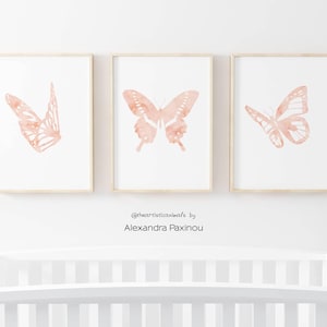 printable butterfly prints set of 3 whole blush pink butterflies. The picture shows how the triptych looks once framed in a nursery over the baby crib. displayed size A4