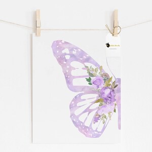 Op de afbeelding: Een aquarelprint van een paarse vlinder vleugel met een tros paarse bloemen en groene bladeren.