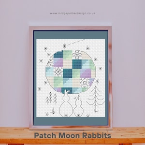 May include: A cross-stitch pattern featuring two rabbits holding a patchwork moon with a blue, green, and purple colour scheme. The moon is surrounded by stars and small trees. The text "Patch Moon Rabbits" is below the image.
