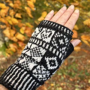May include: Black and white knitted fingerless gloves with a geometric pattern. The gloves are made from a soft, warm yarn and are ideal for keeping your hands warm in the winter.