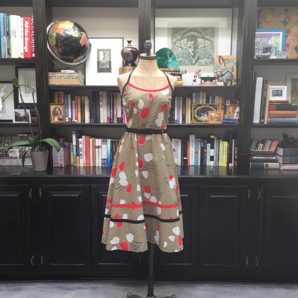 70s does 50s in this just about perfect tan cotton day dress with orange and black flowers crisscrossing back straps buolt in bra & pockets!