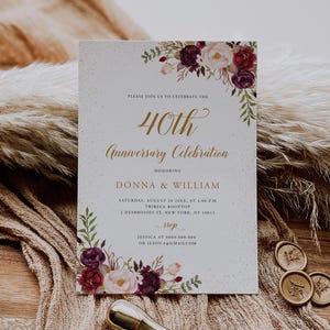 Puede incluir: Una tarjeta de invitación crema para una celebración del 40 aniversario, adornada con arreglos florales en borgoña, rosa y verde. La tarjeta incluye detalles del evento y los nombres Donna & William.