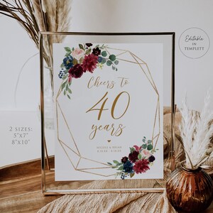 Può includere: Un cartello incorniciato con la scritta "Cheers to 40 years" in oro, circondato da composizioni floreali. Il cartello è esposto in una cornice di vetro trasparente. Il cartello è disponibile nei formati 12,7 cm x 17,8 cm e 20,3 cm x 25,4 cm.