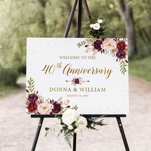 Puede incluir: Un cartel blanco con purpurina dorada y un borde floral en tonos burdeos, rosa y blanco. El cartel dice "Bienvenido al 40 aniversario de Donna & William 18 de agosto de 1982". El cartel está en un caballete.