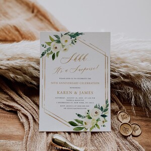 Puede incluir: Una tarjeta de invitaci&oacute;n blanca con bordes geom&eacute;tricos dorados y arreglos florales. El texto dice "Shhh... It's a Surprise!" y anuncia una celebraci&oacute;n del 50 aniversario para Karen & James. Incluye detalles de RSVP.