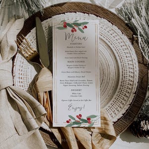 May include: A white menu card with a festive holiday theme. The menu features starters, main course, dessert, and espresso coffee. The card is decorated with a red and green holly sprig.