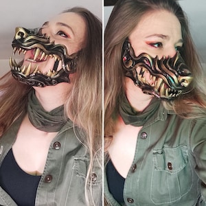 Puede incluir: Una persona con una chaqueta verde y una máscara de lobo dorada y negra. La máscara tiene dientes afilados y un diseño detallado.