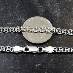 May include: A silver chain necklace with a lobster clasp. The chain is shown next to a US quarter for size comparison.