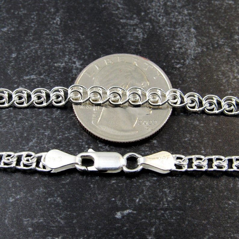 May include: A silver chain necklace with a lobster clasp. The chain is shown next to a US quarter for size comparison.