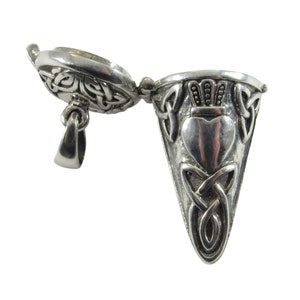 May include: Silver Celtic knot pendant with a heart and crown design. The pendant is a hinged locket that opens to reveal a small compartment inside.