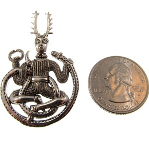 Pu&ograve; includere: Ciondolo in argento raffigurante una figura cornuta seduta su un serpente, con un designo circolare. Il ciondolo &egrave; circa delle dimensioni di una moneta da 25 centesimi di dollaro americano.