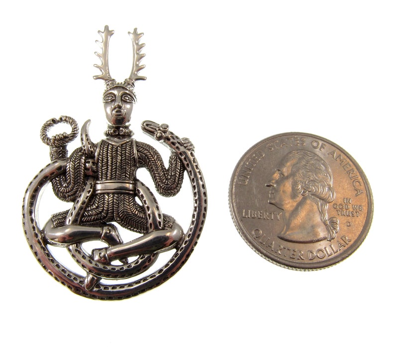 Pu&ograve; includere: Ciondolo in argento raffigurante una figura cornuta seduta su un serpente, con un designo circolare. Il ciondolo &egrave; circa delle dimensioni di una moneta da 25 centesimi di dollaro americano.