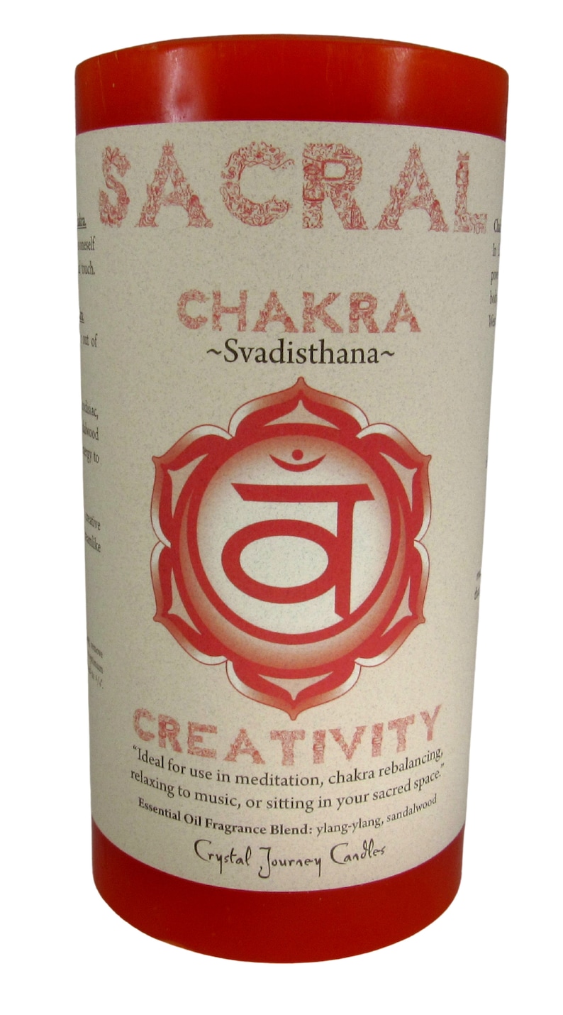 May include: Red candle with a white label that says "Sacral Chakra ~Svadisthana~" and a red symbol with the word "Creativity" below it. The label also says "Ideal for use in meditation, chakra rebalancing relaxing to music, or sitting in your sacred space. Essential Oil Fragrance Blend: ylang-ylang, sandalwood Crystal Journey Candles"