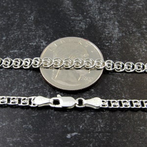 May include: A silver chain necklace with a lobster clasp. The chain is shown next to a US quarter for size comparison.