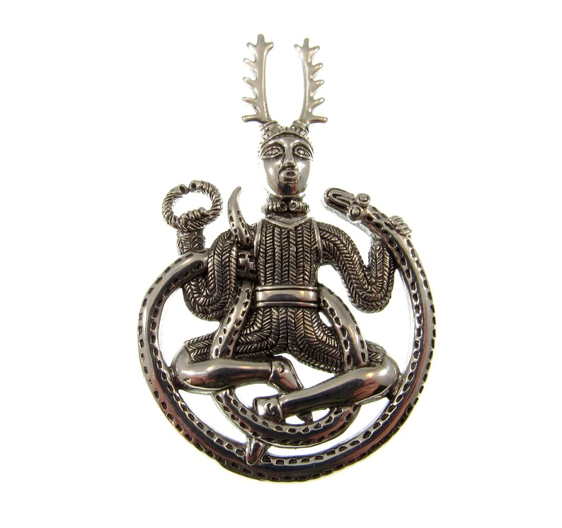 Pu&ograve; includere: Pendente in argento raffigurante una figura cornuta con corna, seduta in un cerchio formato da un serpente. La figura indossa un abito a motivi e ha un viso dettagliato.