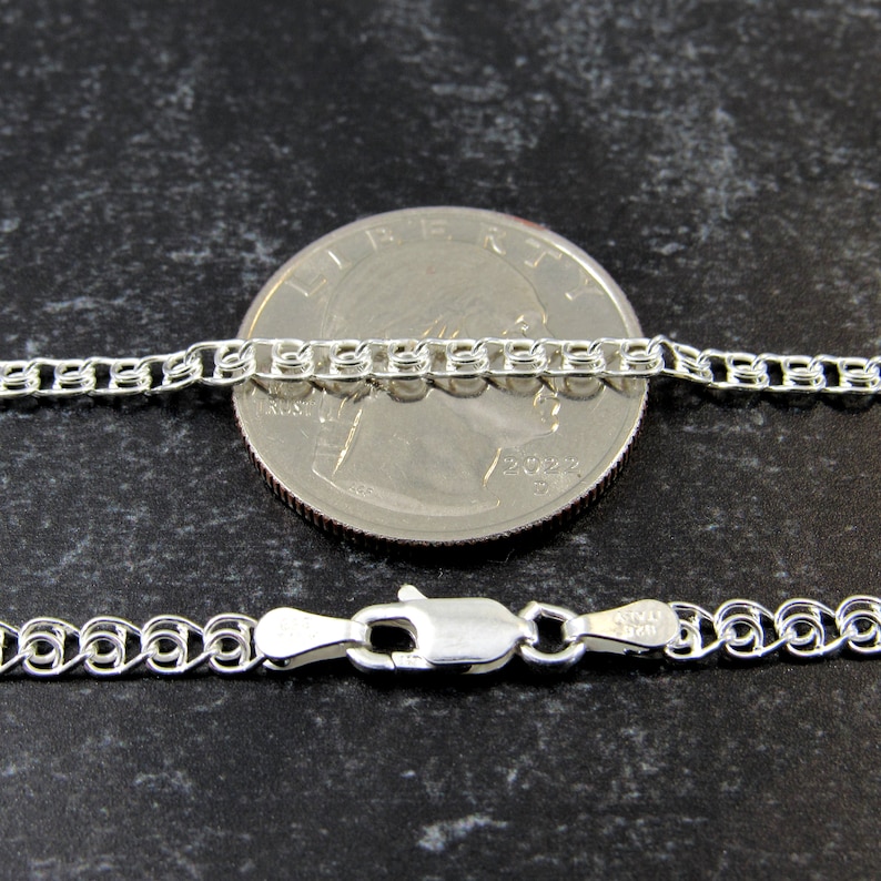 May include: A silver chain necklace with a lobster clasp. The chain is shown next to a US quarter for size comparison.