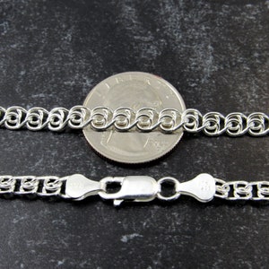 May include: A silver chain necklace with a lobster clasp. The chain is shown next to a US quarter for size comparison.