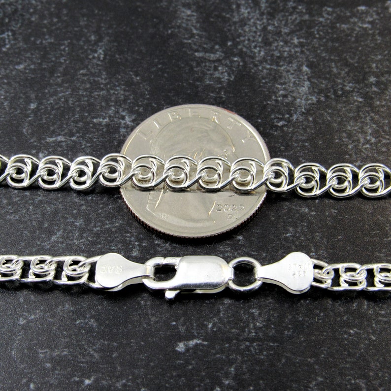 May include: A silver chain necklace with a lobster clasp. The chain is shown next to a US quarter for size comparison.
