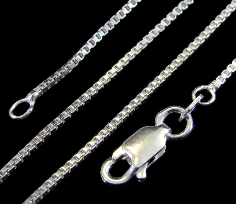 May include: A silver chain necklace with a box chain design and a lobster clasp closure.