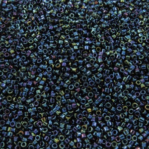 May include: A close-up view of a large quantity of small, dark blue, iridescent seed beads. The beads have a metallic sheen and are scattered randomly.
