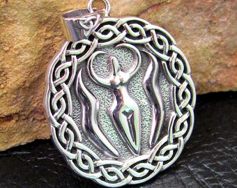 May include: A silver pendant with a Celtic knot border, featuring a central design of a female figure. The pendant has a loop for a chain and is set against a textured backdrop. The design incorporates flowing lines and detailed knotwork.