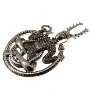 Pu&ograve; includere: Pendente in argento raffigurante una figura cornuta con un serpente avvolto attorno al suo corpo. La figura indossa un'armatura a maglia e ha un viso dettagliato.